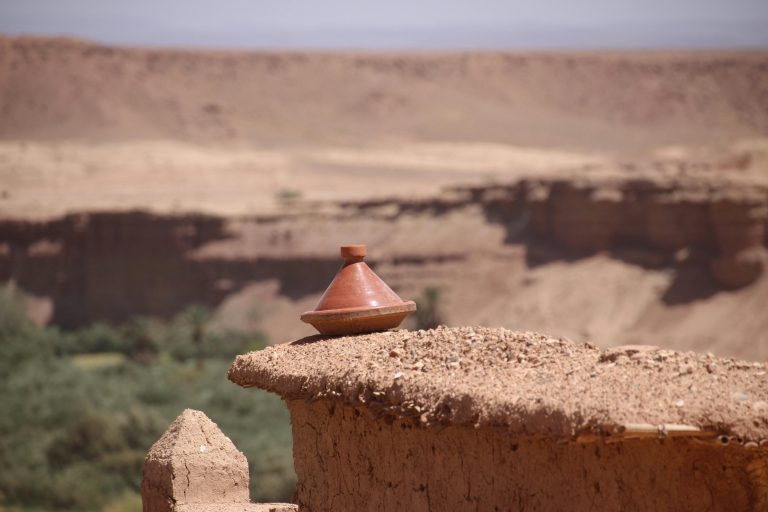 Terra cotta tagine pot on desert wall offers a glimpse into Moroccan culinary culture.